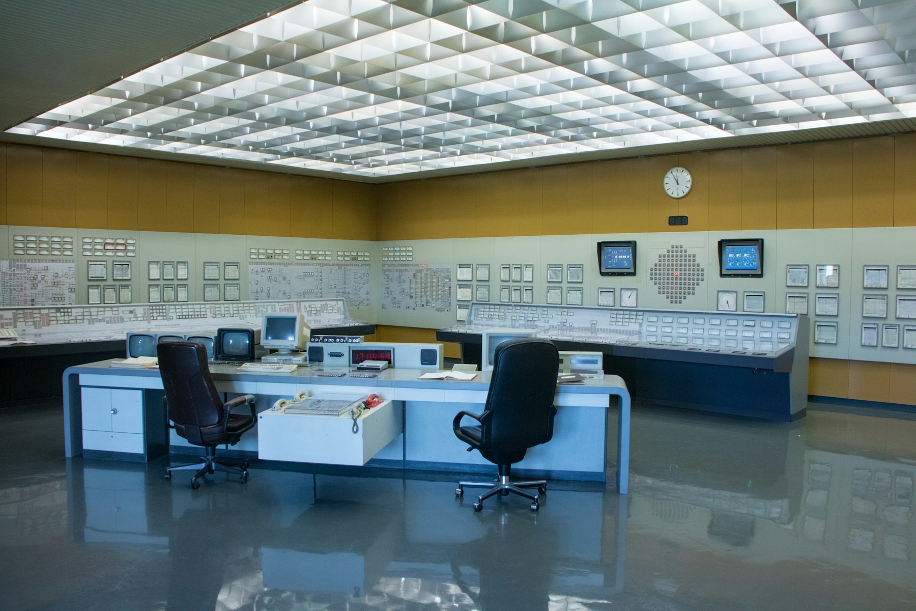 Control room with operator desks facing wall panels